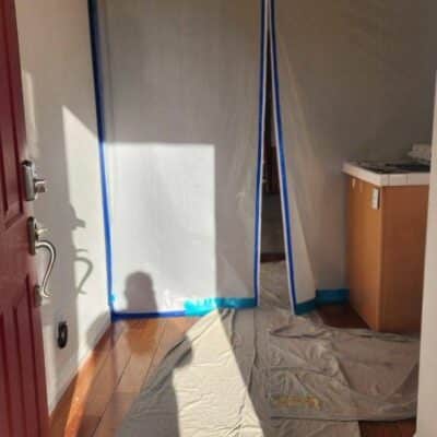 Entryway with plastic sheeting and drop cloths, prepared for renovation work.