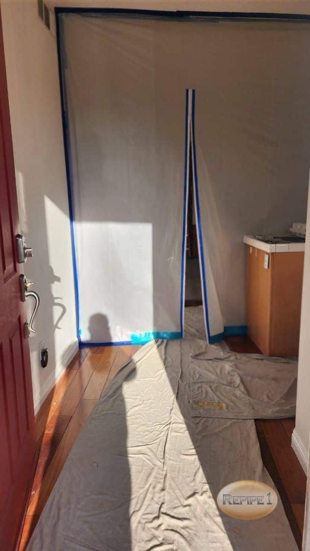 Entryway with plastic sheeting and drop cloths, prepared for renovation work.