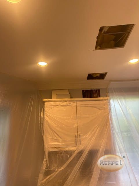 Ceiling with cutouts and plastic-covered cabinets indicating renovation work