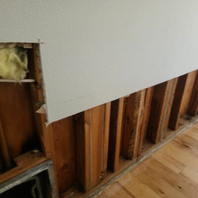 Partially exposed wall with insulation and wooden studs, showing the progress of a renovation or repair project.