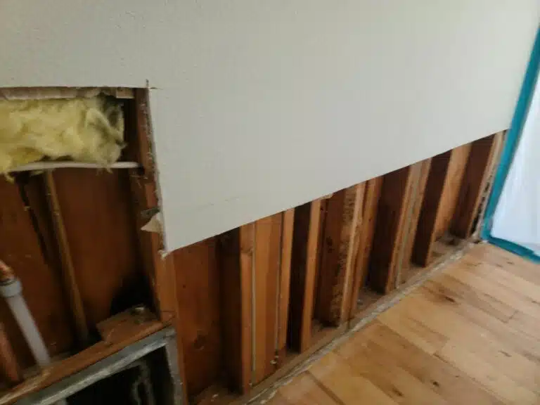 Partially exposed wall with insulation and wooden studs, showing the progress of a renovation or repair project.